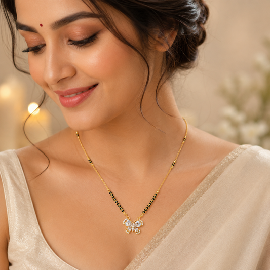 A woman wearing a gold-tone necklace with black bead accents and a floral pendant with clear stones, shown in a warm, softly lit close-up portrait.